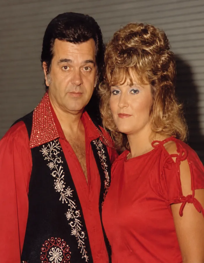 Vicki Lee in a red stage outfit posing backstage with a fellow country performer