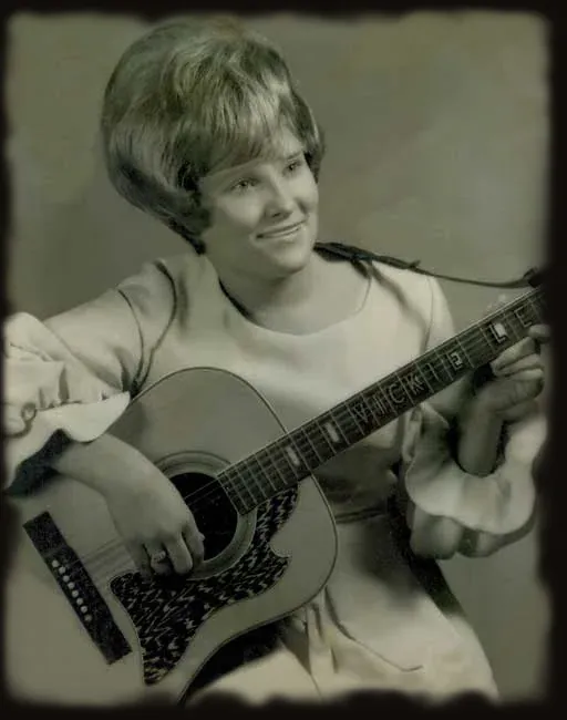 A young Vicki Lee with her acoustic guitar, her name inlaid on the fretboard